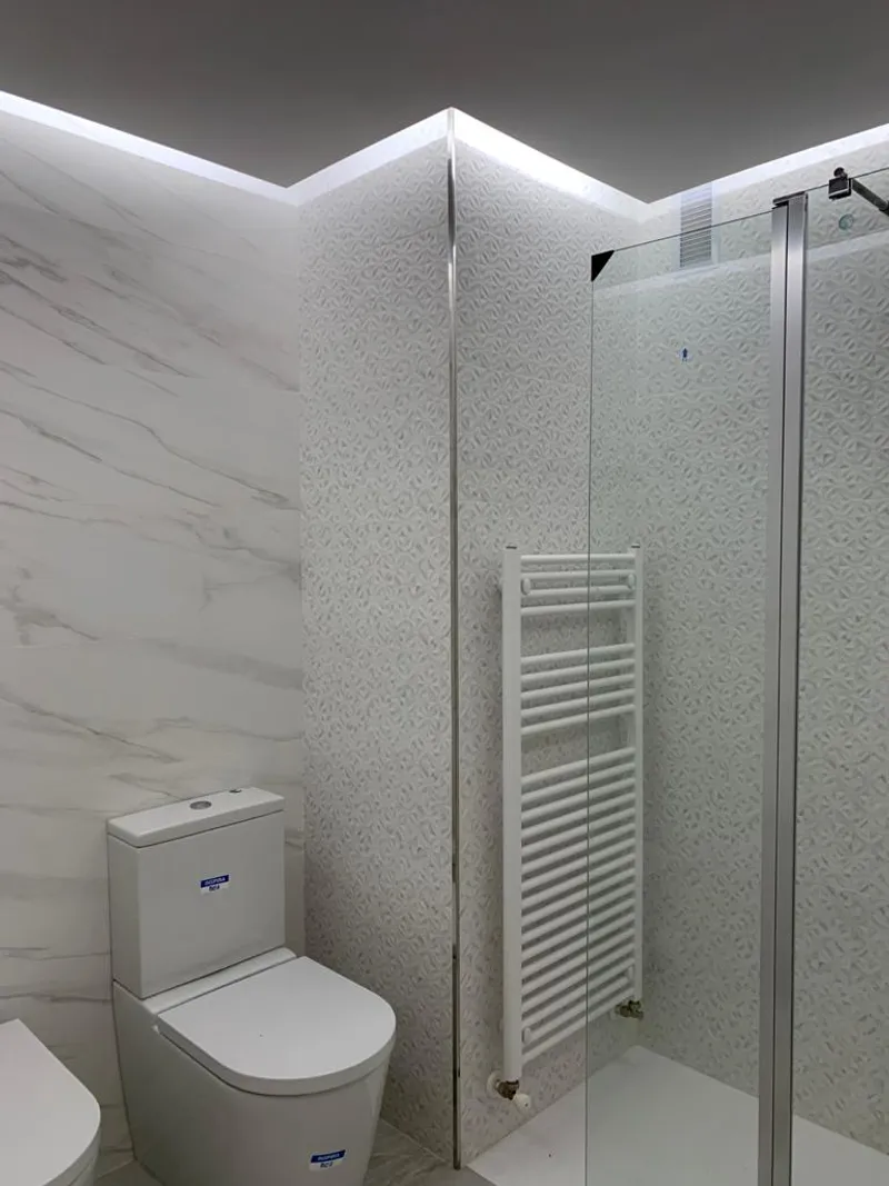 Baño con ducha de mampara e iluminación