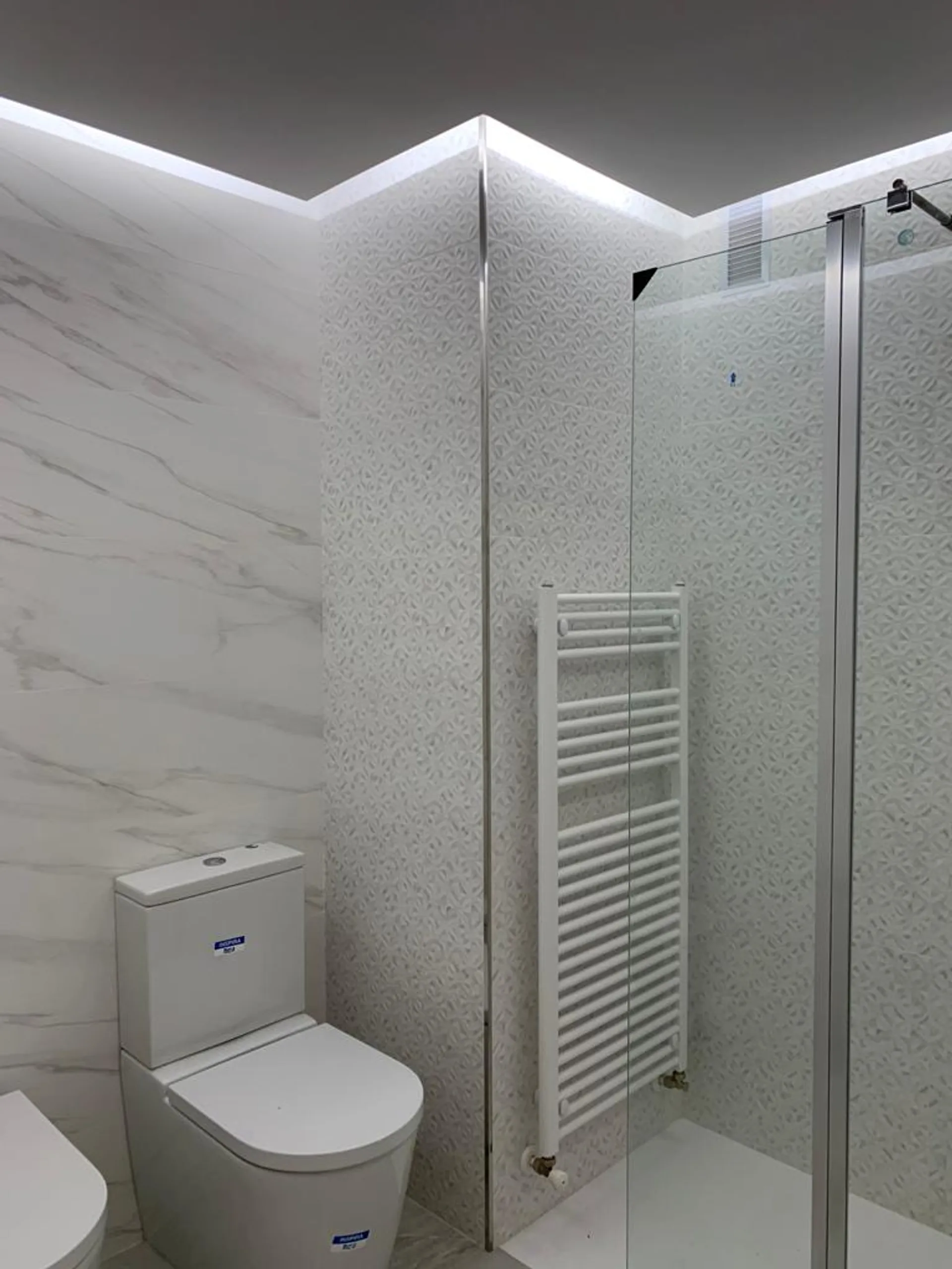 Baño con ducha de mampara e iluminación
