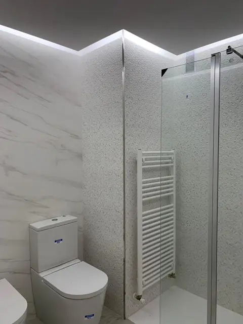 Baño con ducha de mampara e iluminación