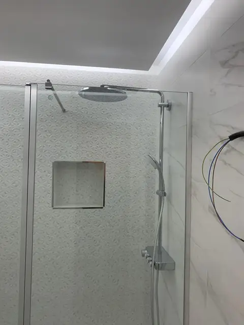 Baño con ducha de mampara e iluminación
