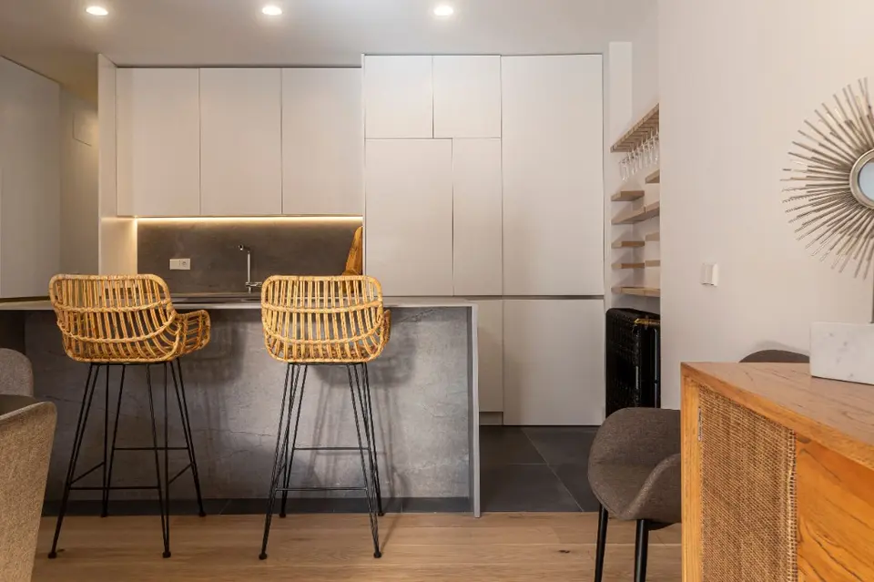 Cocina de diseño con isla en piedra y taburetes de rattan