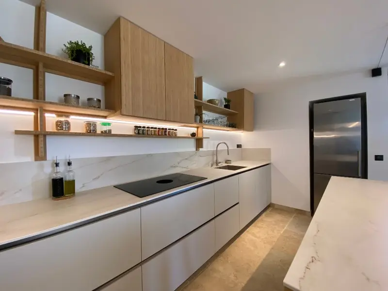 Cocina a medida con estantería de madera e inducción integrada